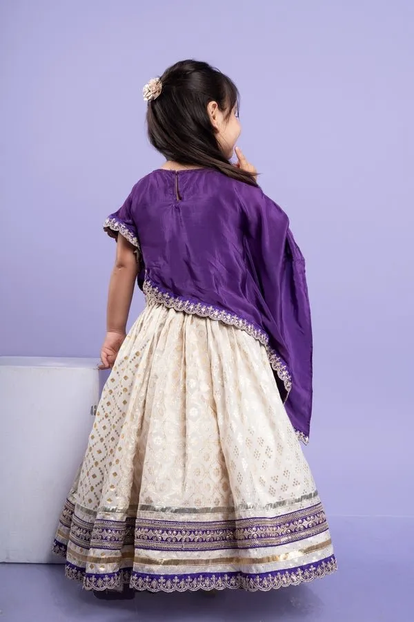 Elegant purple cape-style top with golden embroidery paired with a white lehenga adorned with delicate golden motifs and a broad purple and gold border.