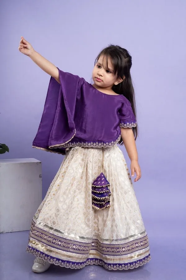 Elegant purple cape-style top with golden embroidery paired with a white lehenga adorned with delicate golden motifs and a broad purple and gold border.